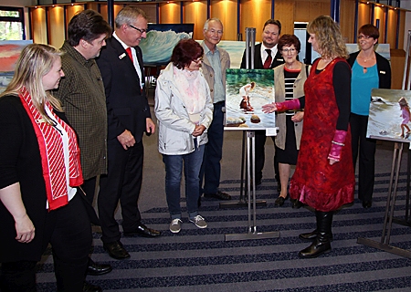Die Künstlerin Birgit Schön-Schneider (Mitte) beschrieb Gästen der Ausstellungseröffnung, wie ihre fotorealistischen Bilder entstehen. Ganz links: Geschäftsstellenleiterin Sara Deckers und 3.v.l.: Vorstand Bernd Zibell.
