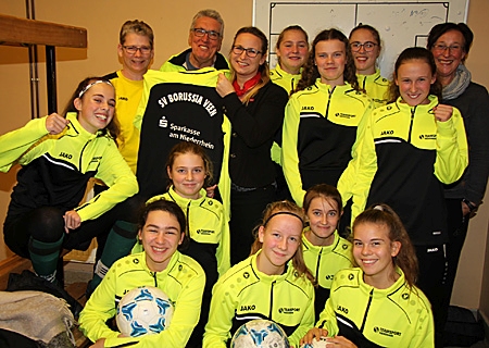 Die U15-Mädchen von SV Borussia Veen freuen sich mit Trainerin Dunja Gooßens (2.v.l.), Co-Trainer Theo Bühren und Betreuerin Hanne Steinmann über den ersten Satz Jacken für die Mannschaft. Kathrin Hüsch von der Sparkasse hatte sie vor Beginn des Trainings in die Kabine gebracht.